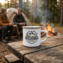 Emaillebecher mit silbernem Rand und Logo beim Camping am Lagerfeuer vor einem Zelt