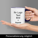 Zwei Hände präsentieren eine weiße Keramiktasse mit kobaltblauem Henkel; auf der Vorderseite Platzhalter „Ihr Logo / Text / Bild + Name“ – zeigt Personalisierungs­möglichkeit beim Keramiktassen Bedrucken