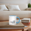 Weißer Keramikbecher mit hellblauem Henkel und Platzhalter „Ihr Design hier“ steht auf einem Couchtisch – inspirierendes Mockup zum tassen bedrucken lassen
