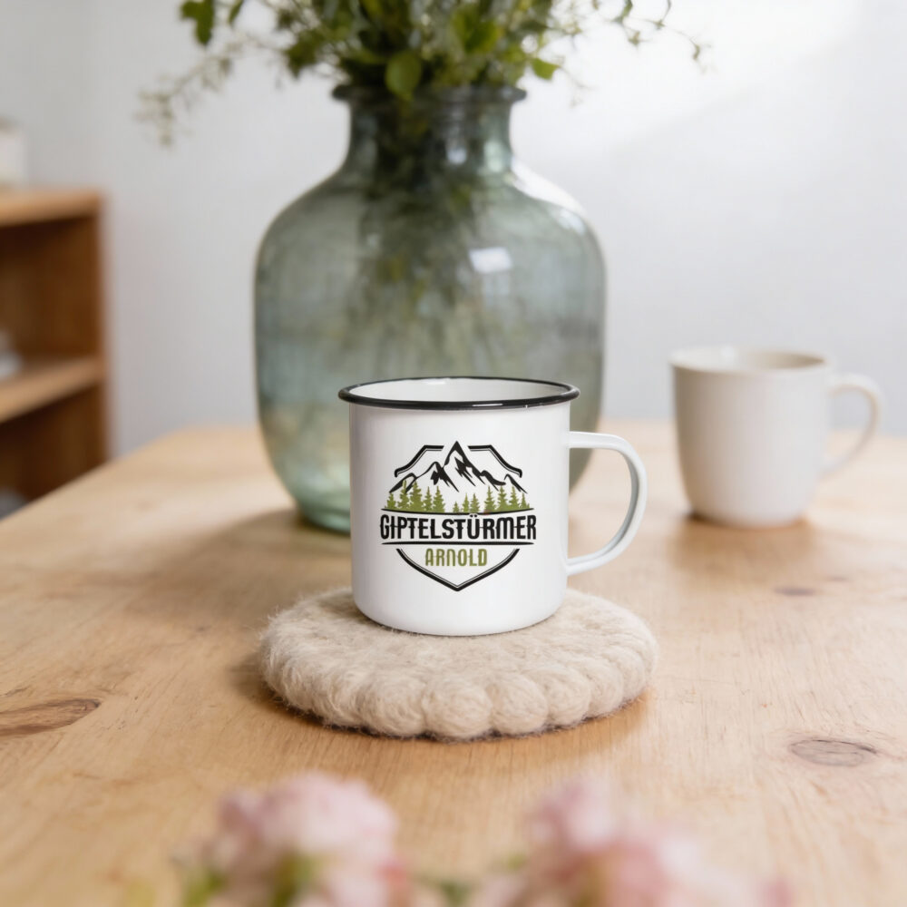 Emaillebecher schwarzer Rand mit Logo-Druck Emaillebecher mit schwarzem Rand und Berg-Logo auf Holztisch mit Vase und Blumen